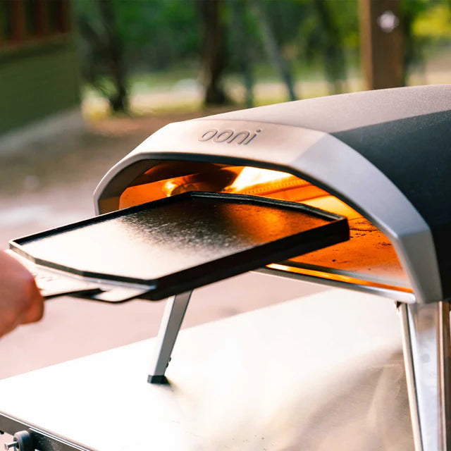 Portable pizza oven with 'Onni' branding on a blurred outdoor background