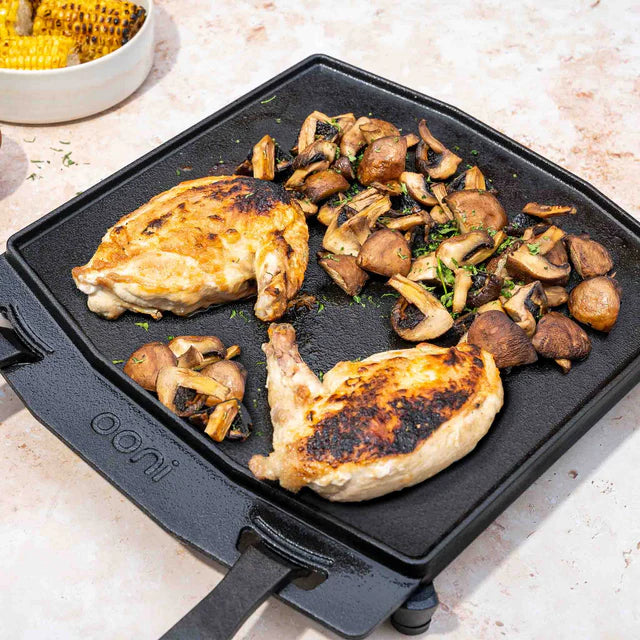 Grilled chicken and mushrooms on a cast iron skillet with 'Oni' branding.