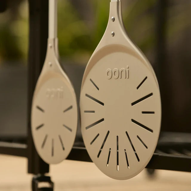 Two ooni pizza stones hanging against a blurred outdoor background