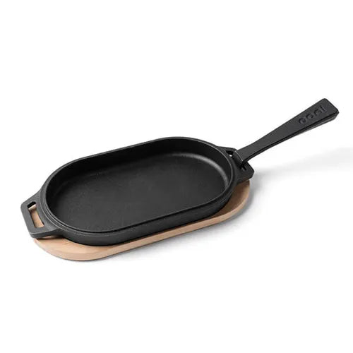 Black cast iron skillet with wooden base on a white background