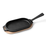 Black cast iron skillet with wooden base on a white background