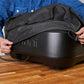 Person covering a black device with a cover on a wooden surface